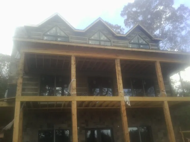 Dormers and porch framing on a large log home under construction — Roof Coating work by our crew in Libertytown