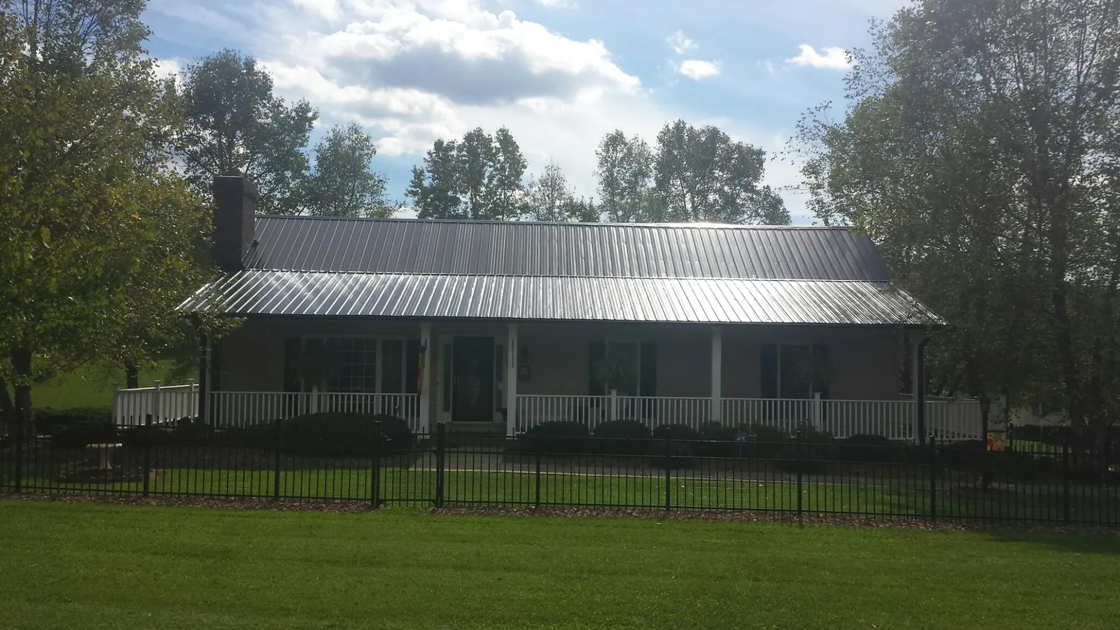 Gray metal roof on a brick ranch with a full width front porch — Gutter Guard Installation work by our crew in Libertytown