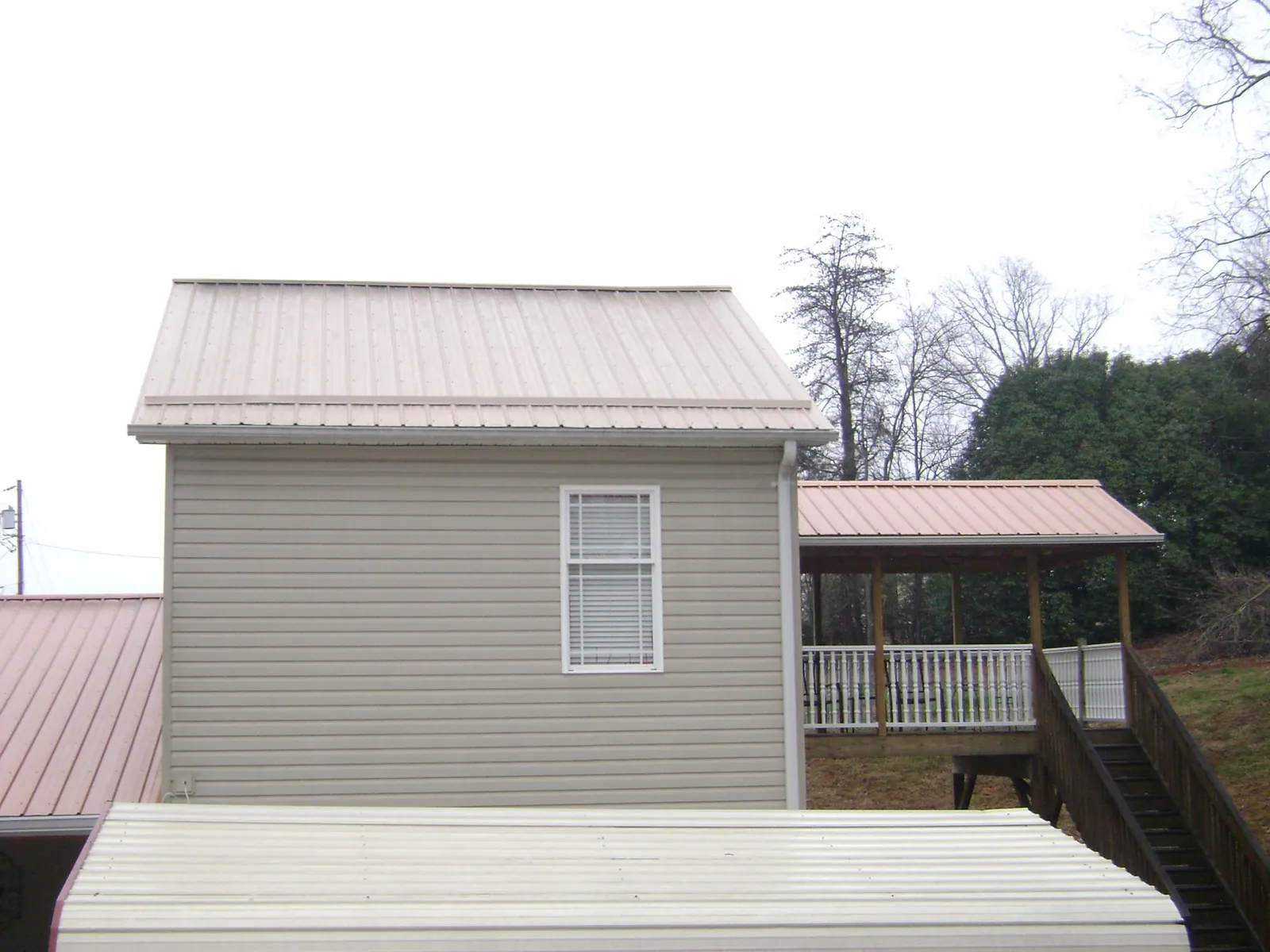 Tan metal roofs on a two story addition and attached porch, from a Roof Replacement job in Libertytown